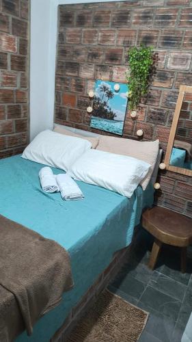 a bed with two pillows on it next to a brick wall at Só Alegria in Paulista