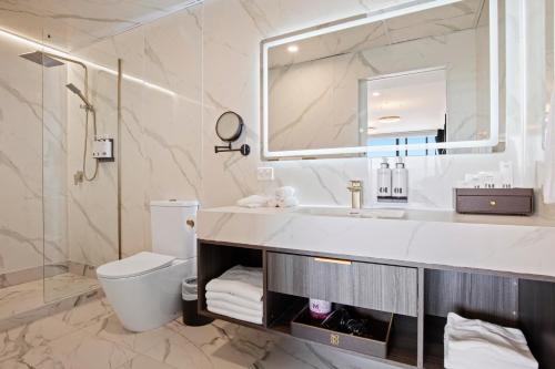 a bathroom with a sink and a toilet and a mirror at SOHO Hotel Auckland in Auckland