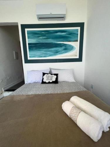 a bedroom with a bed with two pillows and a painting at Pousada Mirante do Atalaia Oficial II in Arraial do Cabo