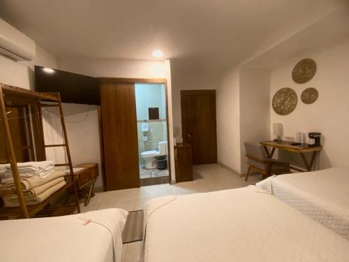a bedroom with two beds and a table and a mirror at Hotel Punto Oriente Tonala in Tonalá