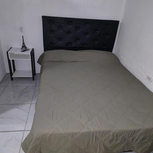 a bed with a black headboard and a side table at Hospedaje El Colibri in Ezeiza