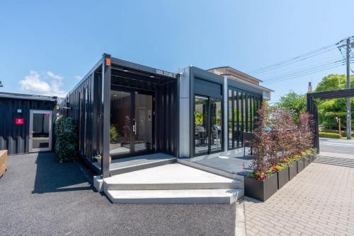 a black house with glass doors on a street at HOTEL R9 Kujukuri "ex Casual Resort COFF Ichinomiya" in Ichinomiya