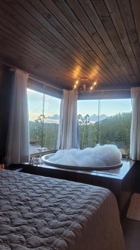a bedroom with a bed and a large window at Chalé Recanto do Pimenta 02 in Venda Nova do Imigrante