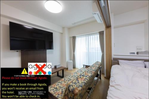 a hotel room with a bed and a flat screen tv at Tomattoco KASUMI in Yamagata