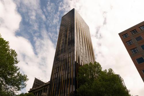 a tall glass building with a sky in the background at Quincy Hotel Melbourne in Melbourne