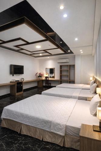 two beds in a large room with a tv at Miền Tây Hotel in Can Tho