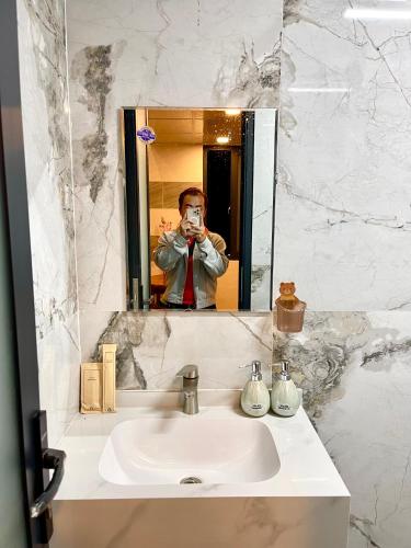 a man taking a picture of himself in a bathroom mirror at Homestay Phương Chi in Ấp Mỹ Phước
