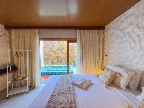a bedroom with a large bed and a large window at Hotel Kanto Do Chico Conceito in Icaraí