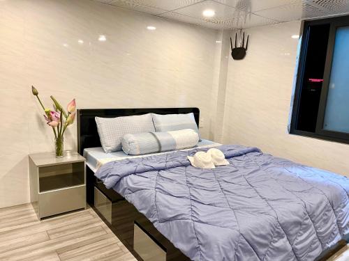 a bedroom with a bed with purple sheets and a vase of flowers at Homestay Phương Chi in Ấp Mỹ Phước