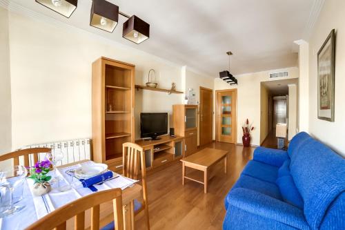 sala de estar con sofá azul y mesa en Apartamentos Legazpi, en Albacete