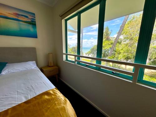 a bedroom with a bed and a large window at The Beachfront in Trinity Beach