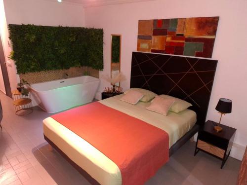 a bedroom with a large bed and a bath tub at Le Maloha in Le Gosier