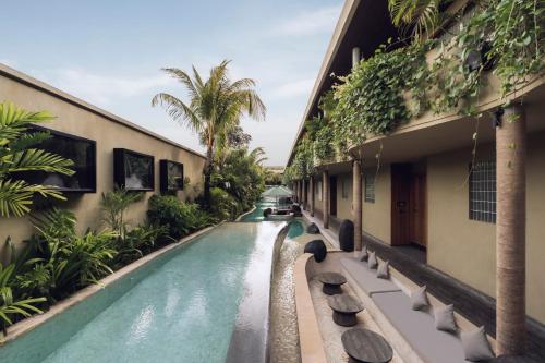 a swimming pool next to a building with a resort at Sini Vie Resort & Spa Seminyak by Ini Vie Hospitality in Seminyak
