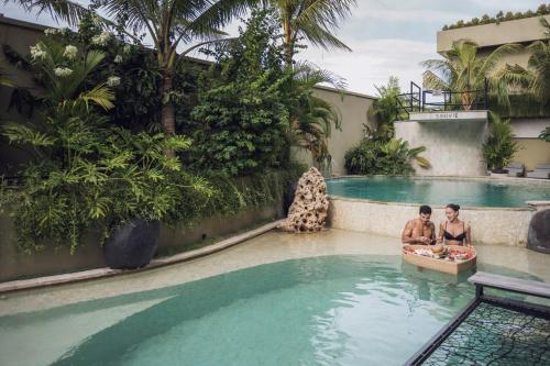 two men in a swimming pool at a hotel at Sini Vie Resort & Spa Seminyak by Ini Vie Hospitality in Seminyak