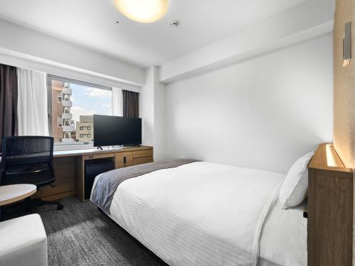 a hotel room with a bed and a desk and a window at Daiwa Roynet Hotel Tokyo Akabane in Tokyo