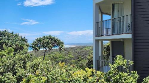 a building with a balcony with a view of trees at Whalewatch Ocean Beach Resort in Point Lookout