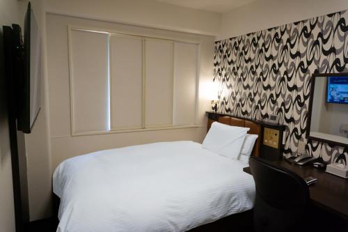 a bedroom with a white bed and a television at APA Hotel Kochi in Kochi