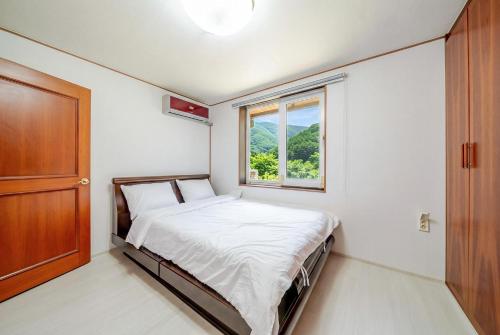 a small bedroom with a bed and a window at Gapyeong Ruba Pension in Gapyeong