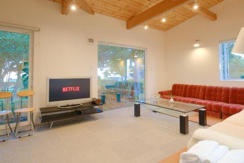 a living room with a red couch and a television at Rental House Towada Yuzuriha Gallery Stay City in Towada