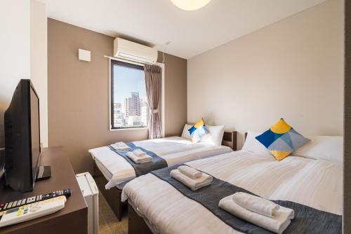 ein Hotelzimmer mit zwei Betten und einem Fernseher in der Unterkunft OKINI - Doyanen Hotels in Osaka