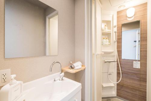ein weißes Badezimmer mit Waschbecken und Dusche in der Unterkunft OKINI - Doyanen Hotels in Osaka