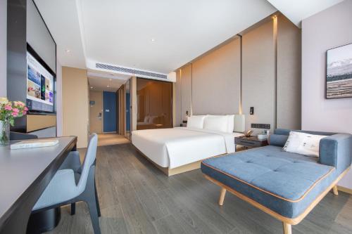 a hotel room with a bed and a couch at Atour Hotel Hefei Yaohai Heping Road in Hefei
