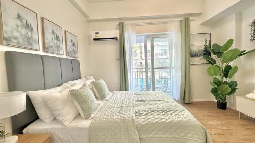 a bedroom with a white bed and a window at Stylish Studio Unit near Airport w Pool and WiFi in Pusok