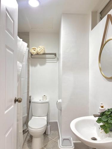 a white bathroom with a toilet and a sink at Stylish Studio Unit near Airport w Pool and WiFi in Pusok