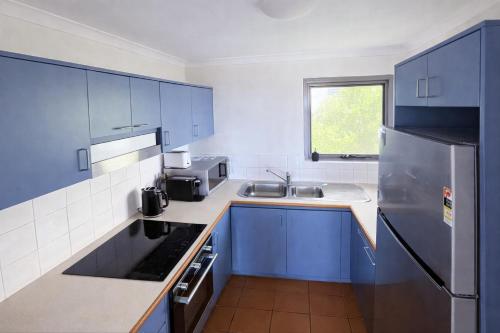 a kitchen with blue cabinets and a stainless steel refrigerator at Scarborough Beach Front Resort - Shell Thirteen in Perth