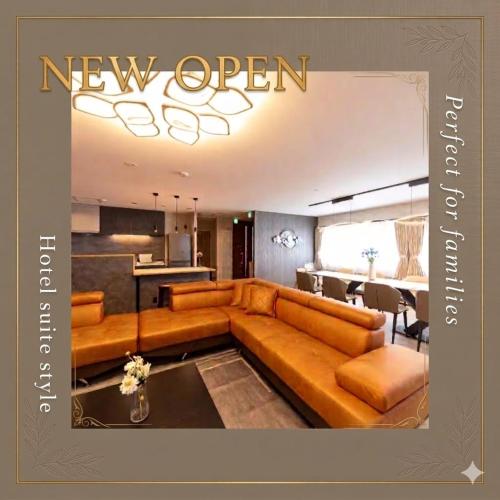 a living room with a brown couch and a kitchen at The SKY in Sapporo