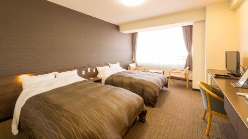a hotel room with two beds and a desk at グリーンピア三陸みやこ in Miyako
