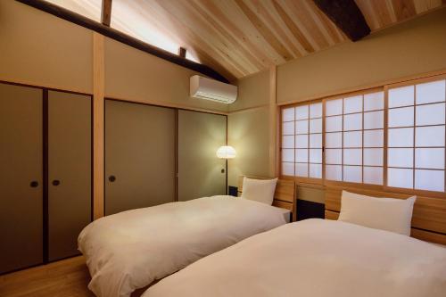 a bedroom with two beds and a window at Ayaginu Machiya House in Kyoto