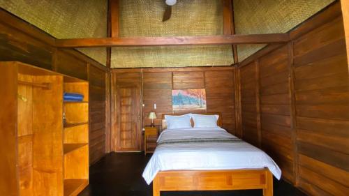 a bedroom with a bed in a wooden wall at Katah Montana Villa in Tonoboyo