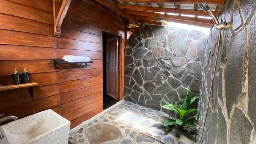 a bathroom with a stone wall and a plant at Katah Montana Villa in Tonoboyo