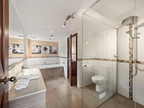 a bathroom with a tub and a toilet and a sink at Whalers Cove Villas in Dunsborough