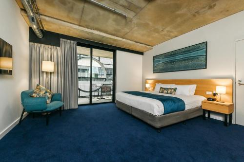 a hotel room with a bed and a chair at Nesuto Curtin Perth Hotel in Perth