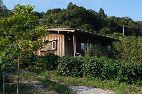 a wooden house with a hill in the background at Lotus Retreat ロータスリトリート 高知空港から車で30分 山のふもとの一棟貸しコテージ in Kami