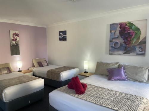 a hotel room with three beds and a couch at Taree Lodge Motel in Taree