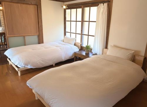 a bedroom with two beds and a window at 古民家ステイshinonome inn in Kitsuki