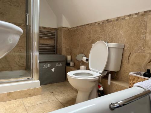 a bathroom with a toilet and a bath tub at Silsoe B&B Master Suite in Silsoe