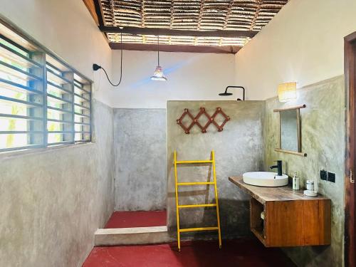 a bathroom with a yellow ladder next to a sink at Bungalow du Lagon in Ambaro