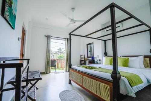 a bedroom with a canopy bed and a balcony at 100Steps Mirissa in Mirissa