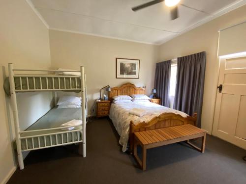 a bedroom with a bed and a bunk bed and a bench at Mirradong Cottage in Berambing
