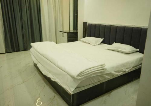 a bed with white sheets and pillows on it at Shri Hari Executive Lodge in Tuljapur