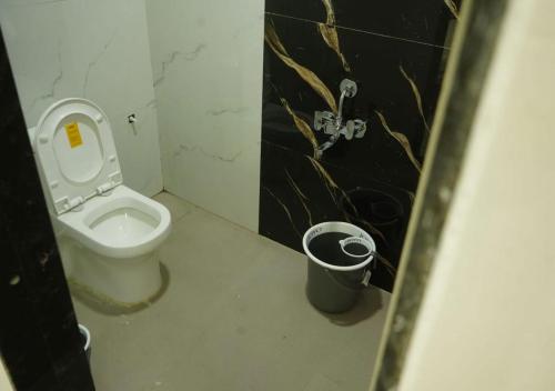 a bathroom with a toilet and a trash can at Shri Hari Executive Lodge in Tuljapur