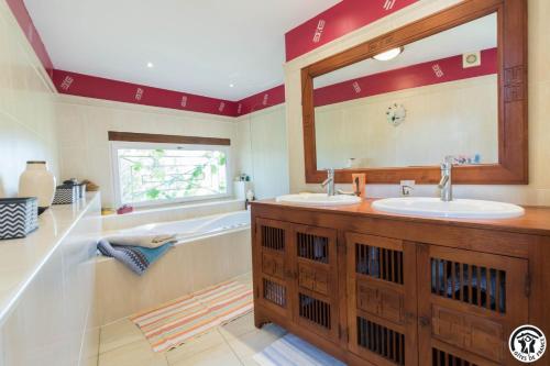 a bathroom with two sinks and a large mirror at La ferme in Ponlat-Taillebourg