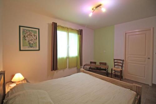 a bedroom with a bed and a window and a table at Le pin parasol in Arnac-la-Poste