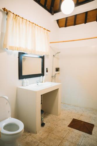 a bathroom with a toilet and a sink and a mirror at Liberty Dive Resort in Tulamben