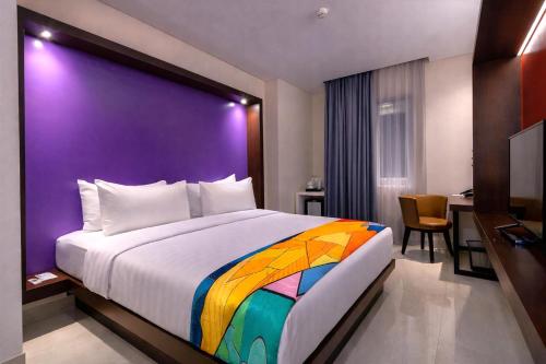 a bedroom with a large bed with a purple wall at Grand Picasso Hotel in Jakarta