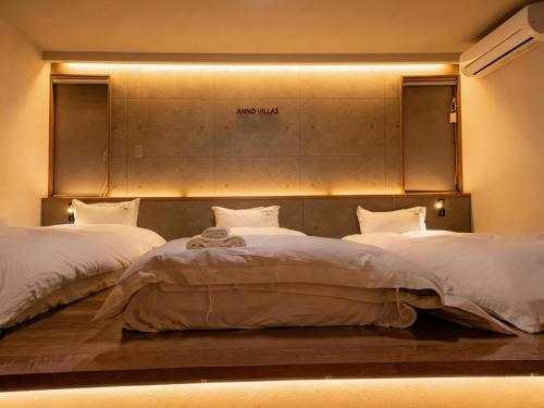 two beds in a room with lights on the wall at Sankando Villa Hotel in Fujikawaguchiko